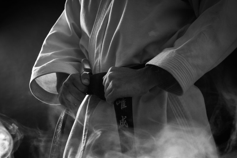 Judoka strikt de zwarte band om een wit judopak